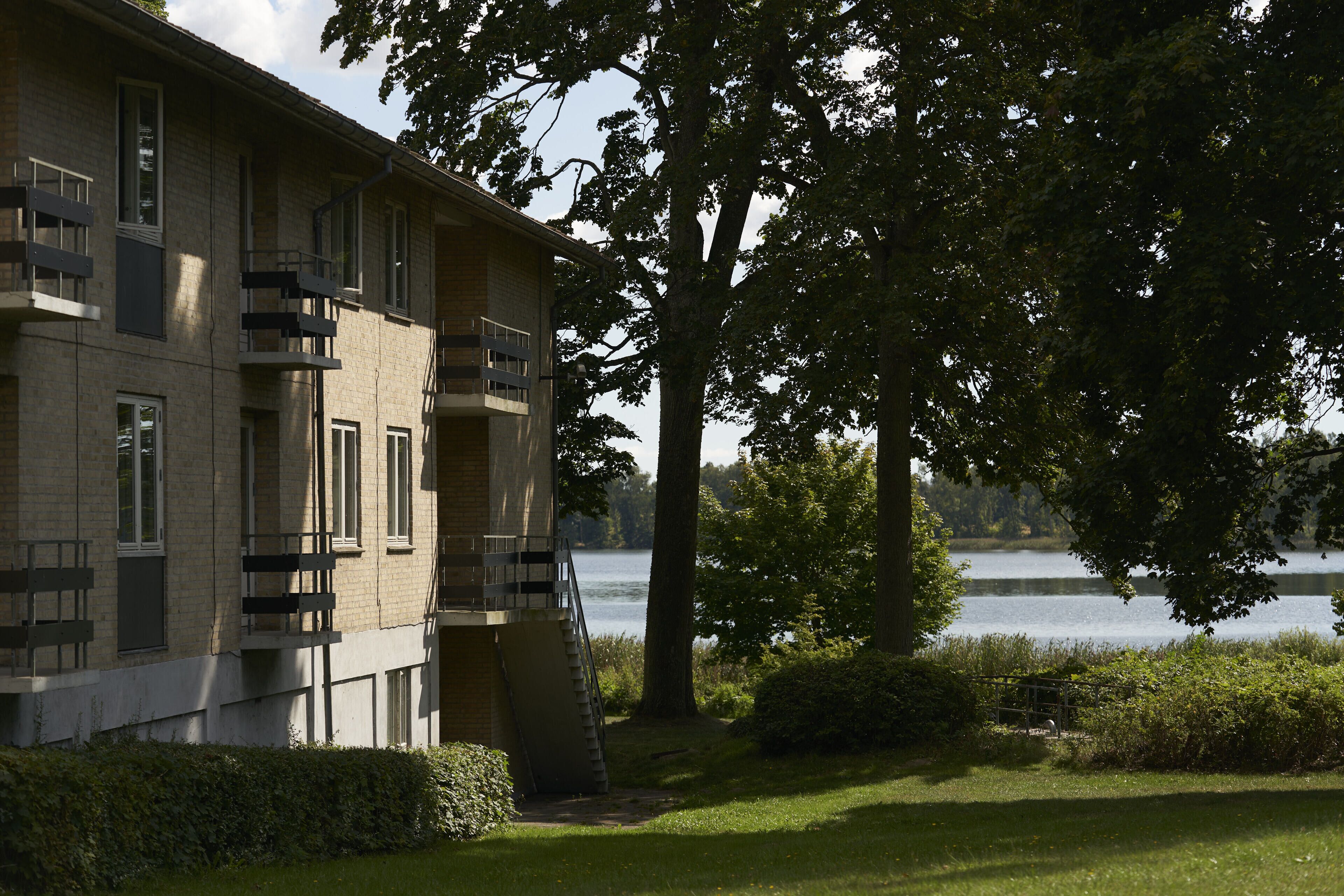 Un edificio de varios pisos con balcones que dan a un lago.