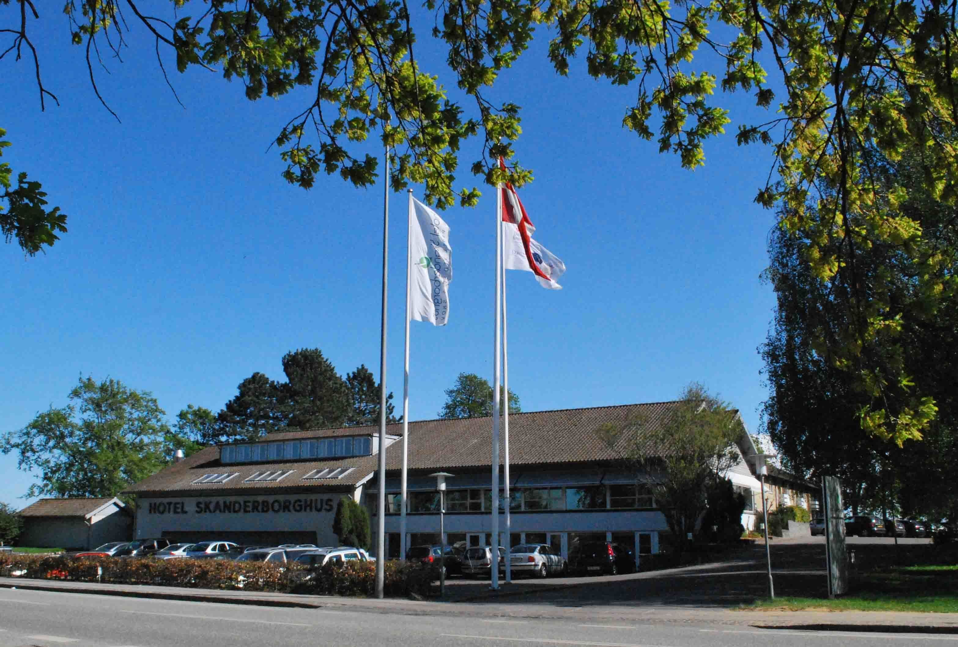 Un hotel con un letrero que dice "HOTEL SKANDERBORGHUS" y dos banderas en asta.