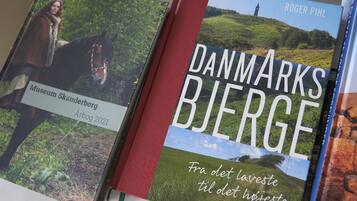 Twee boeken met de titels 'Museum Skanderborg' en 'De Bergen van Denemarken'.