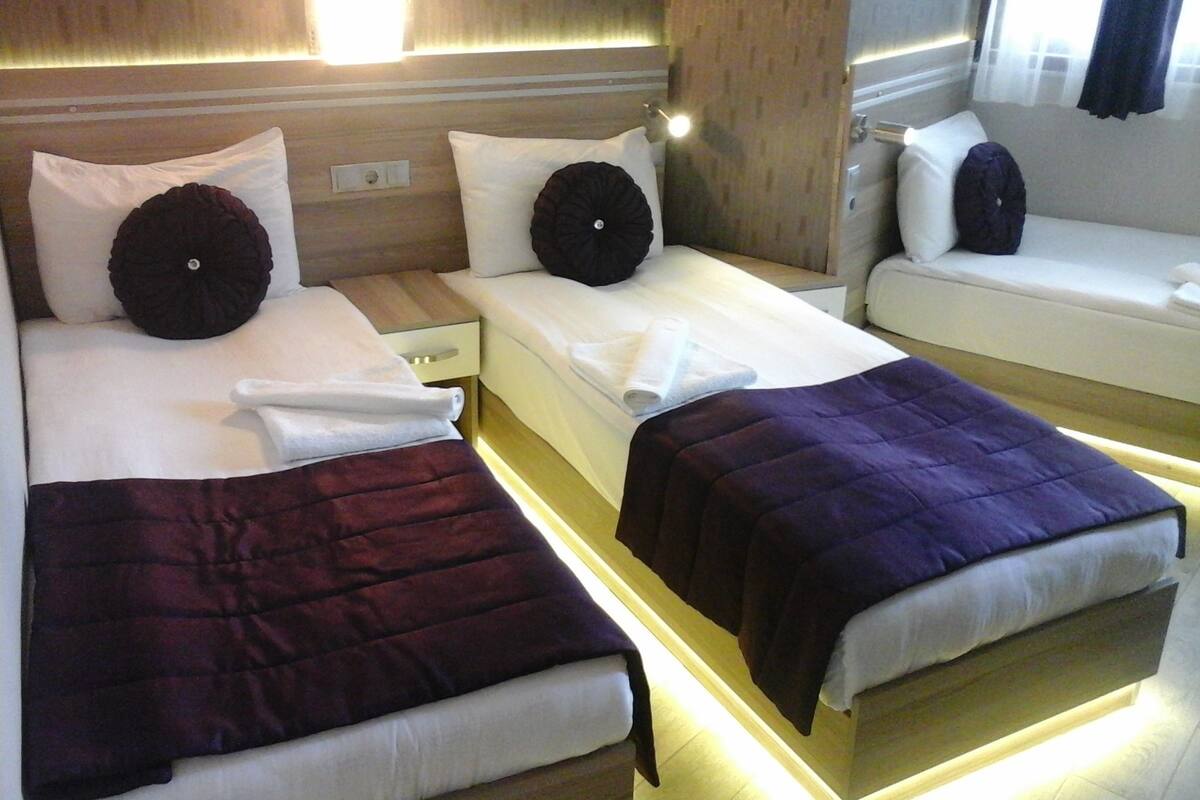 Et hotelværelse med to enkeltsenge, hver med pude og dyne.