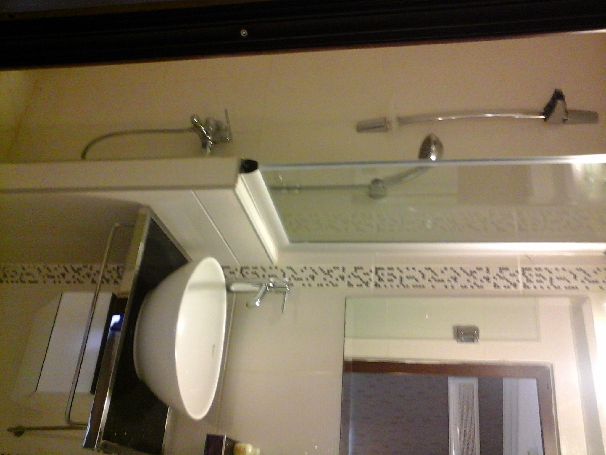 A bathroom with a glass shower enclosure, a white sink, and a towel rack.
