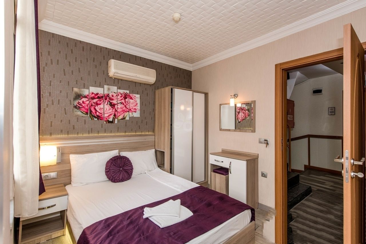 A hotel room with a bed, a nightstand, a mirror, a wardrobe, and a staircase leading to another room.