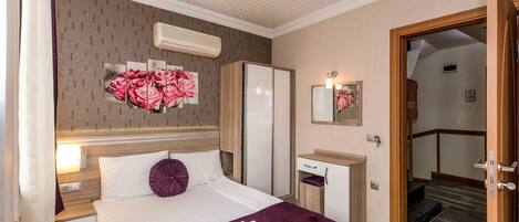 A hotel room with a bed, a nightstand, a mirror, a wardrobe, and a staircase leading to another room.