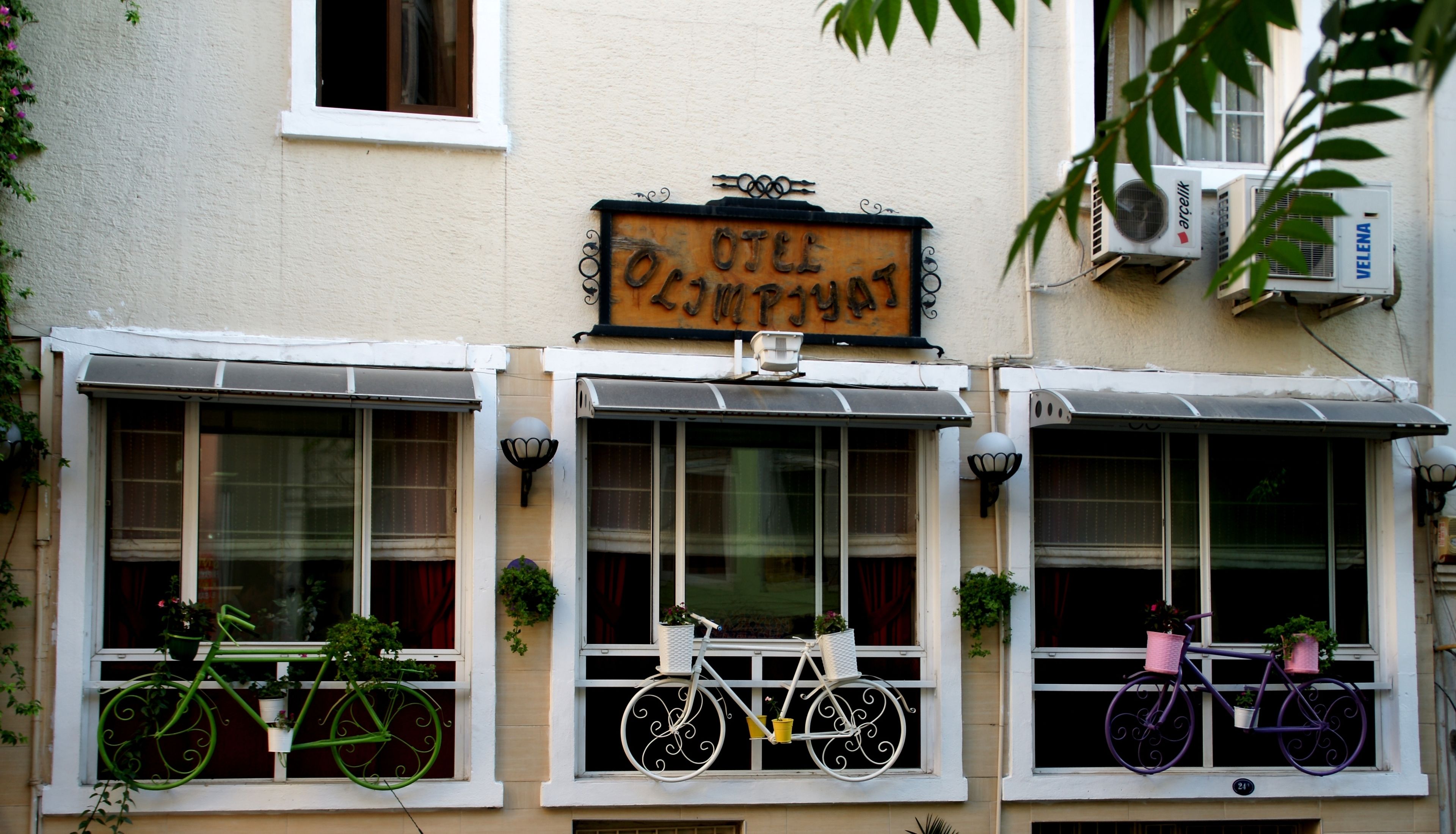 A building with three windows, each with a bicycle and potted plants. A sign above reads "Otte".