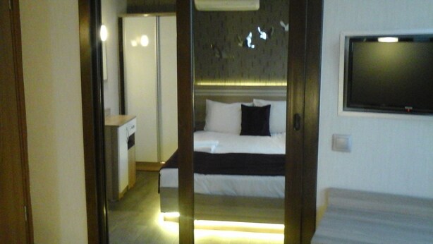 Quarto de hotel com cama, televisão presa na parede e porta deslizante para um banheiro.