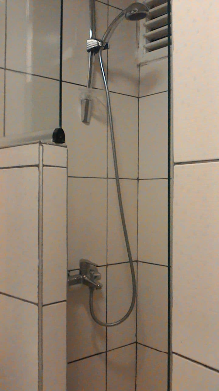 Une douche équipée d’un pommeau de douche à main et de commandes murales.