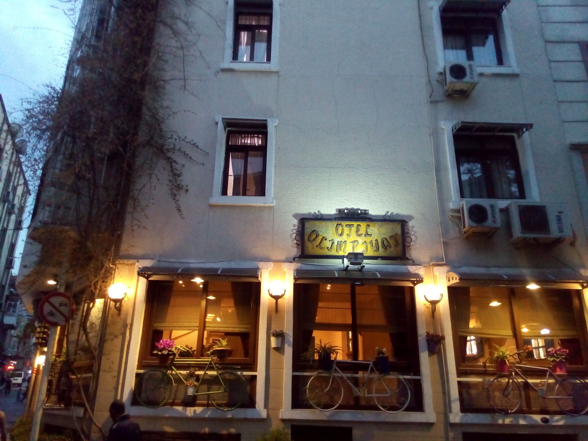 A building with a sign that reads "OITE OJIMPUYAT" and multiple windows with bicycles parked outside.