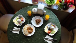 Mesa de café da manhã com pratos de comida, uma xícara de café e um vaso de flores.