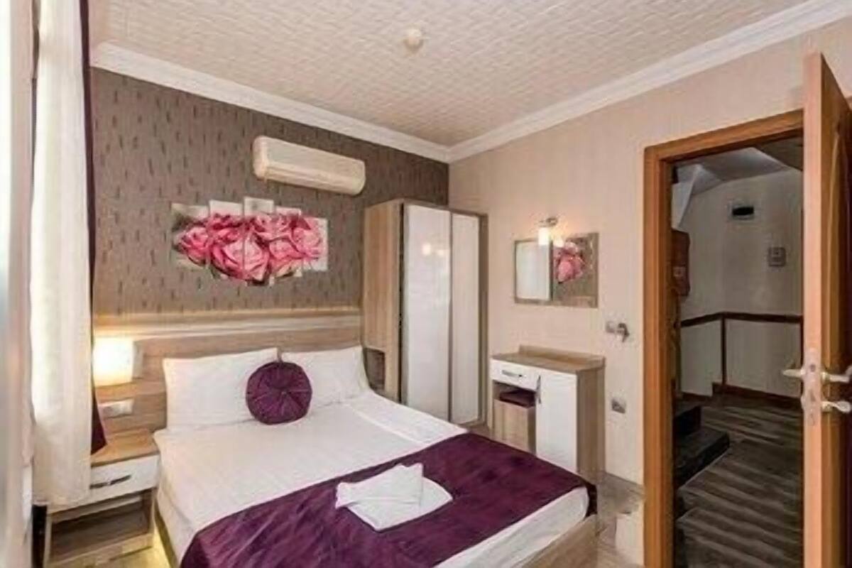 Et hotelværelse med seng, natbord, kommode og et spejl.