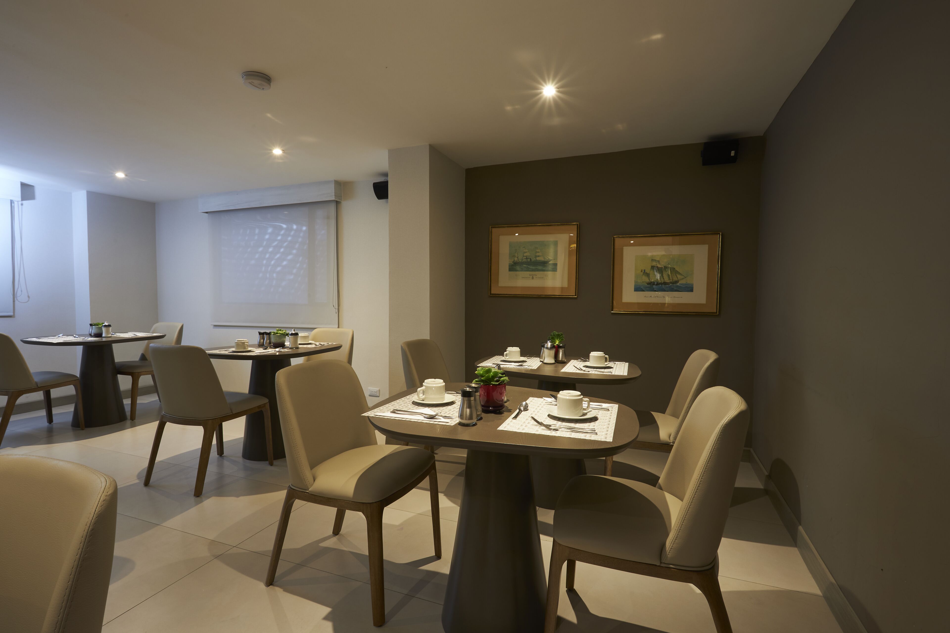 Un comedor moderno con mesas redondas, sillas y obras de arte enmarcadas en las paredes.