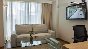 A modern living room with a sofa, a glass coffee table, a TV mounted on the wall, and a chair. - Hotel Saint Simon (Bogotá)