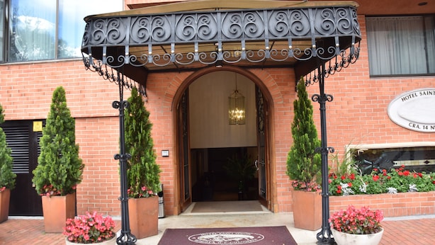 A hotel entrance with a wrought iron canopy, brick facade, and a doormat with a logo. - Hotel Saint Simon (Bogotá)