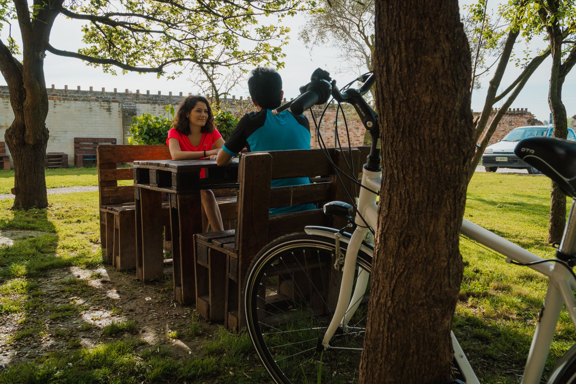 Una mesa de madera y bancos en un parque, con una bicicleta estacionada cerca.