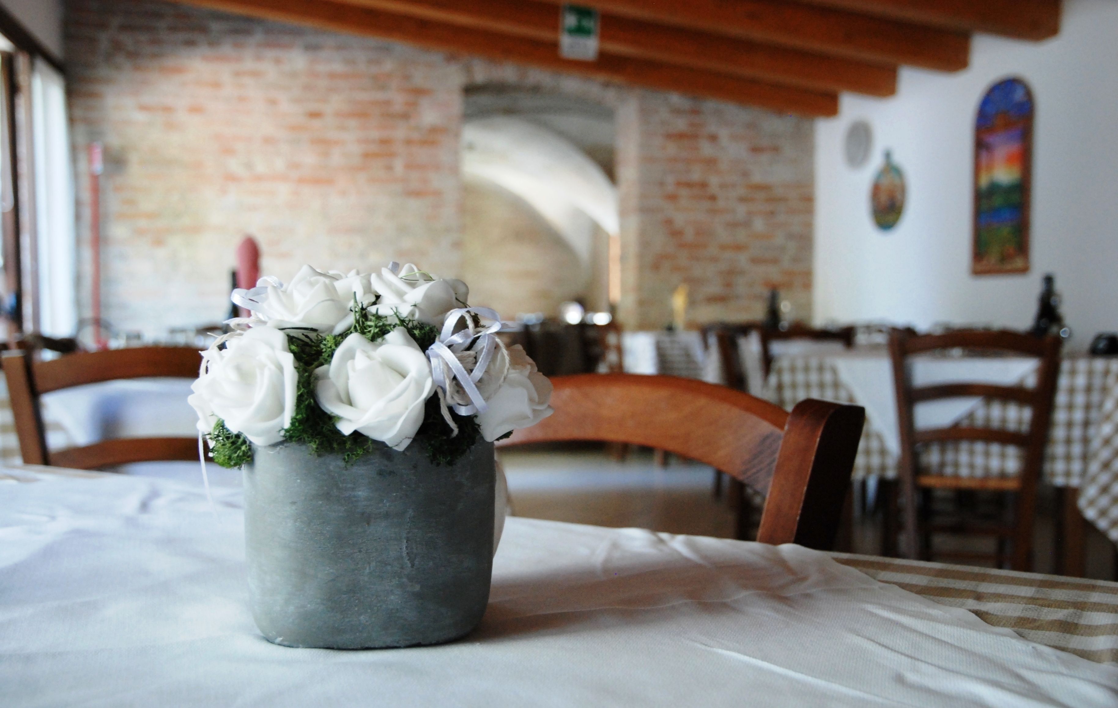 A dining area with a rustic brick wall, wooden chairs, and a table with a white tablecloth.
