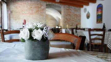 A dining area with a rustic brick wall, wooden chairs, and a table with a white tablecloth.