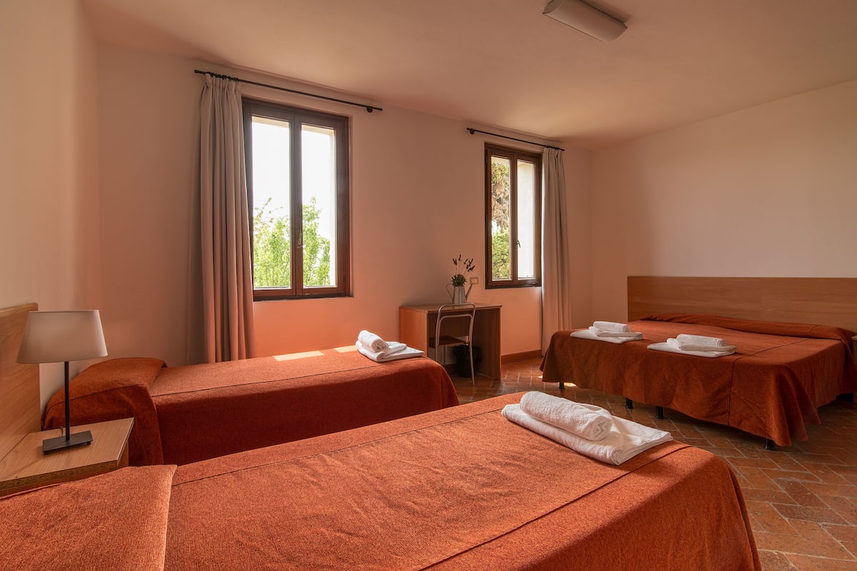 A hotel room with two beds, a desk, and a chair.