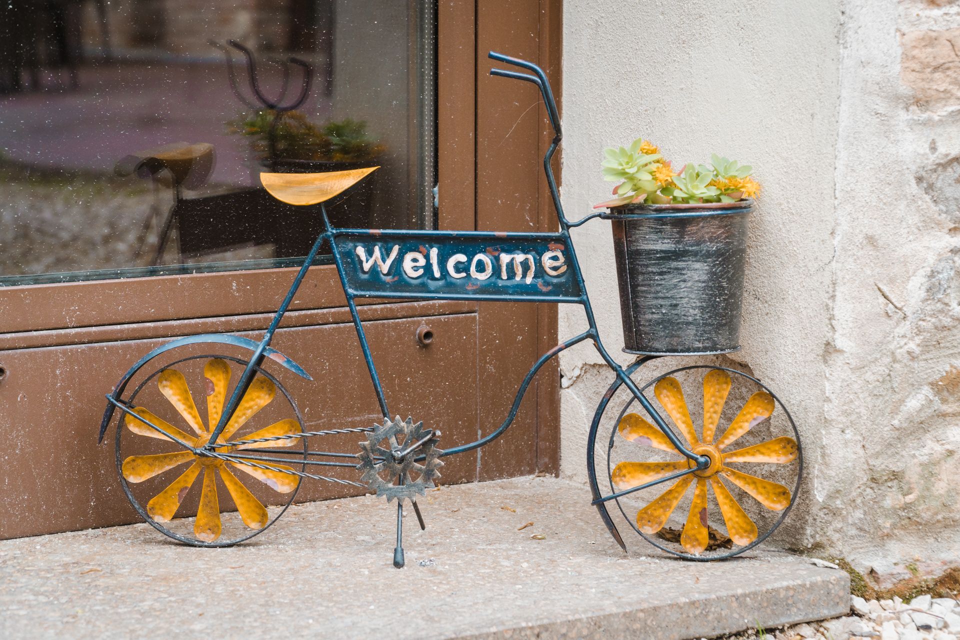 A vintage bicycle with a 'Welcome' sign and a basket of flowers.