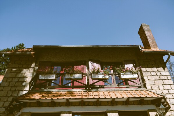A building with a tiled roof, a brick chimney, and a balcony with flower boxes. - Hostellerie Du Lys - Hôtel & Restaurant (Lamorlaye)