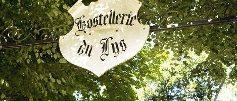 A sign with the text "Gasthof zur Post" against a backdrop of green foliage.