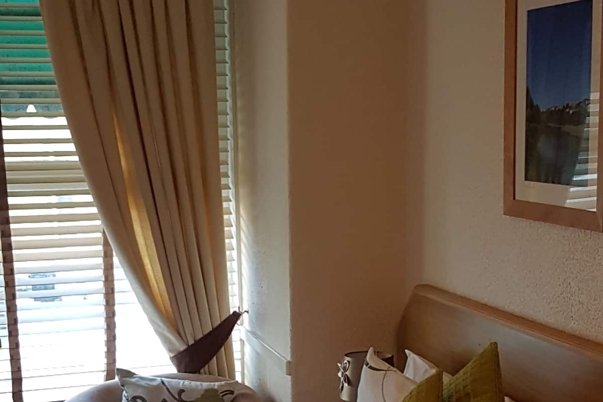 A hotel room with a bed, a chair, and a window with curtains.