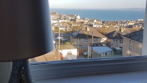 A view from a window overlooking a residential area with houses and a body of water in the distance. - Trelinda Hotel (Newquay)