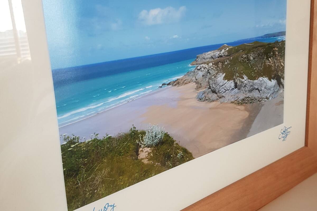 A framed landscape photograph of a beach with rocky cliffs and a clear sky.