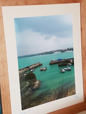 A framed photograph of a harbor with boats docked at piers, clear water, and a distant cityscape. - Trelinda Hotel (Newquay)