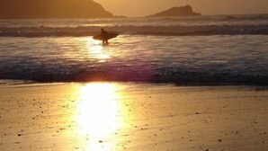 A beach scene with a surfer walking towards the ocean at sunset. - Trelinda Hotel (Newquay)