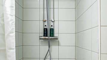 A small, tiled shower stall with a showerhead and a handheld shower attachment.