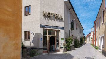 A hotel entrance with a sign, a door, and a cobblestone street.