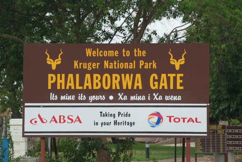 A sign welcoming visitors to Kruger National Park at the Phalaborwa Gate, featuring logos for ABSA and Total.