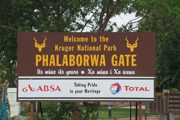 A sign welcoming visitors to Kruger National Park at the Phalaborwa Gate, featuring logos for ABSA and Total. - Sunbird Lodge (Phalaborwa)