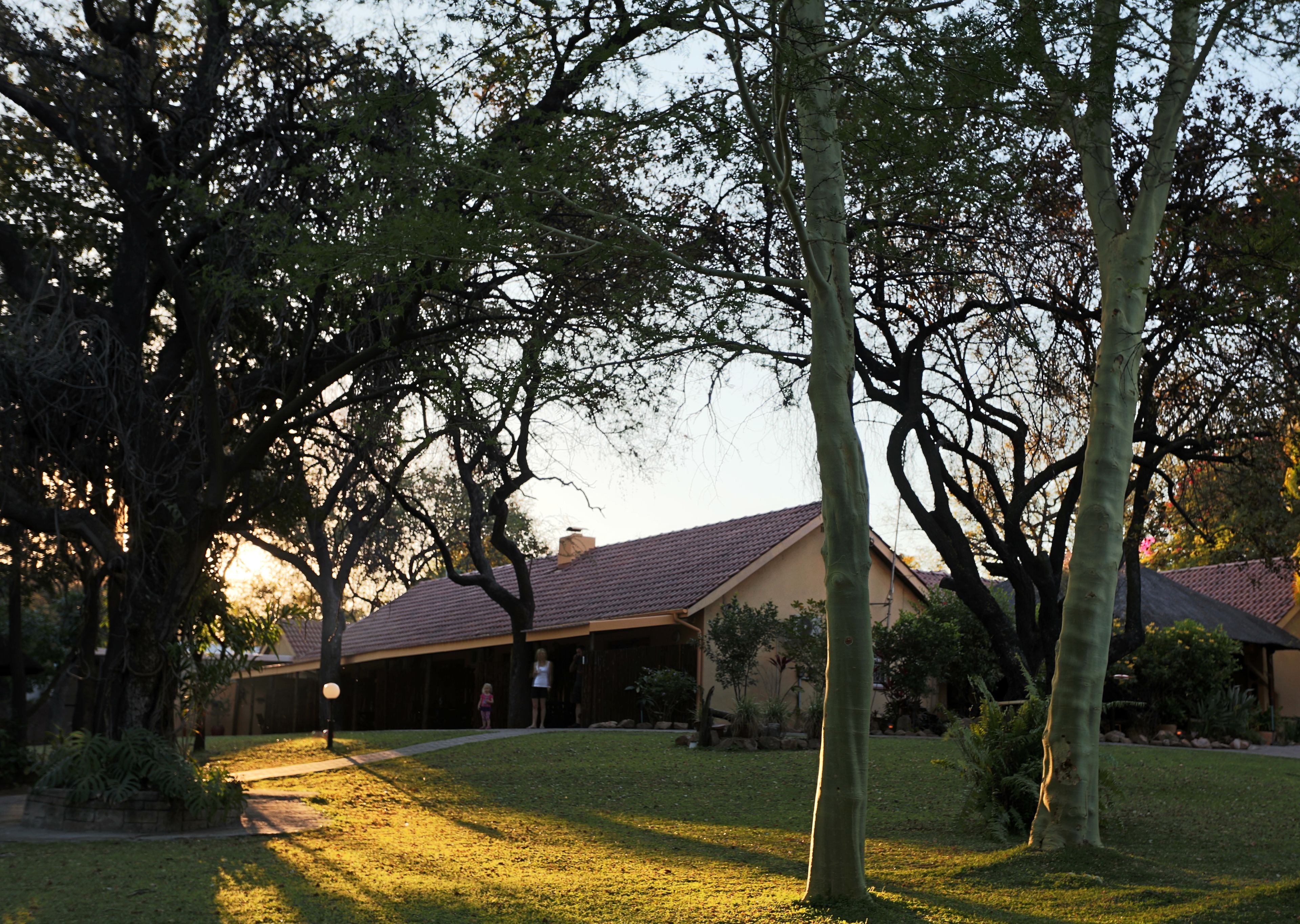 A house with a covered patio, surrounded by trees and a lawn.