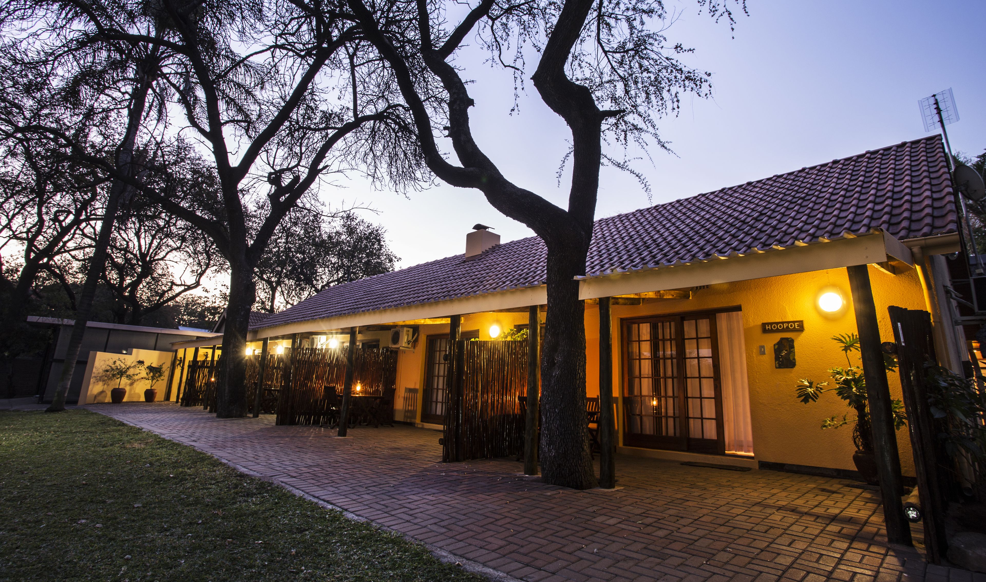 A building with a tiled roof, a sign reading "HOOPOE," and a paved walkway leading to the entrance.
