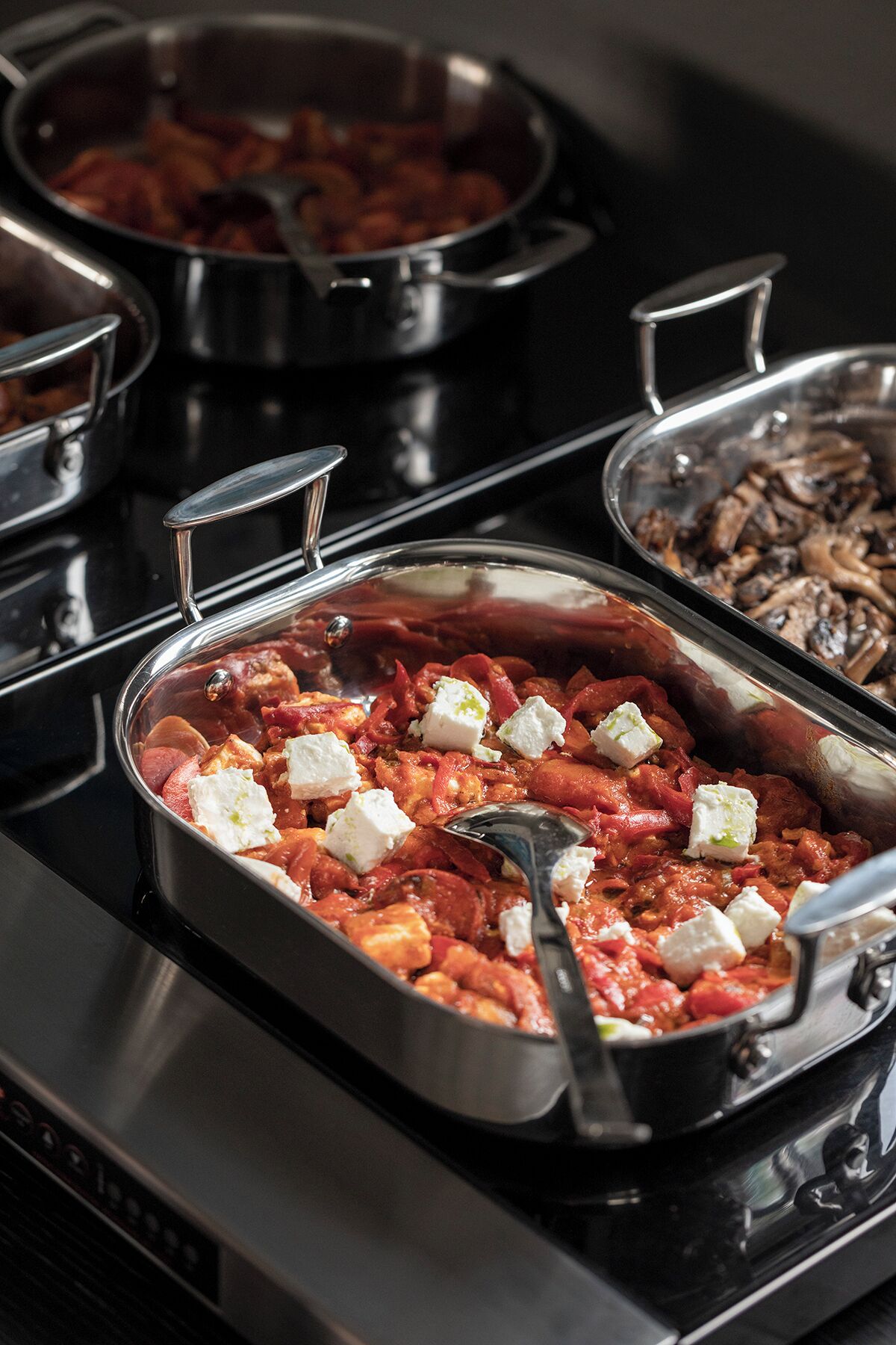 Un bufé con diversos platos, incluyendo un plato a base de tomate con queso y una bandeja de champiñones.