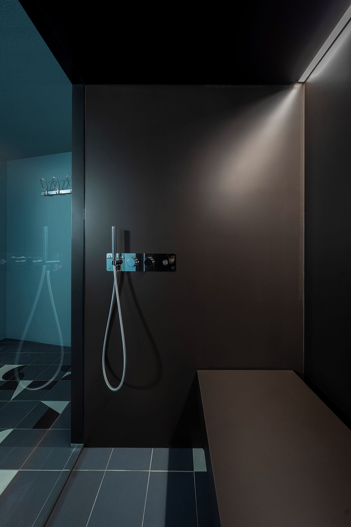 A modern bathroom with a dark wall, a shower area, and a towel rack.
