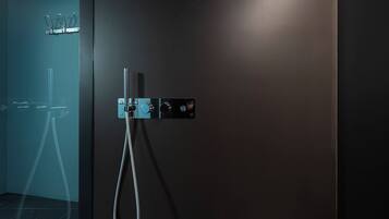 A modern bathroom with a dark wall, a shower area, and a towel rack.