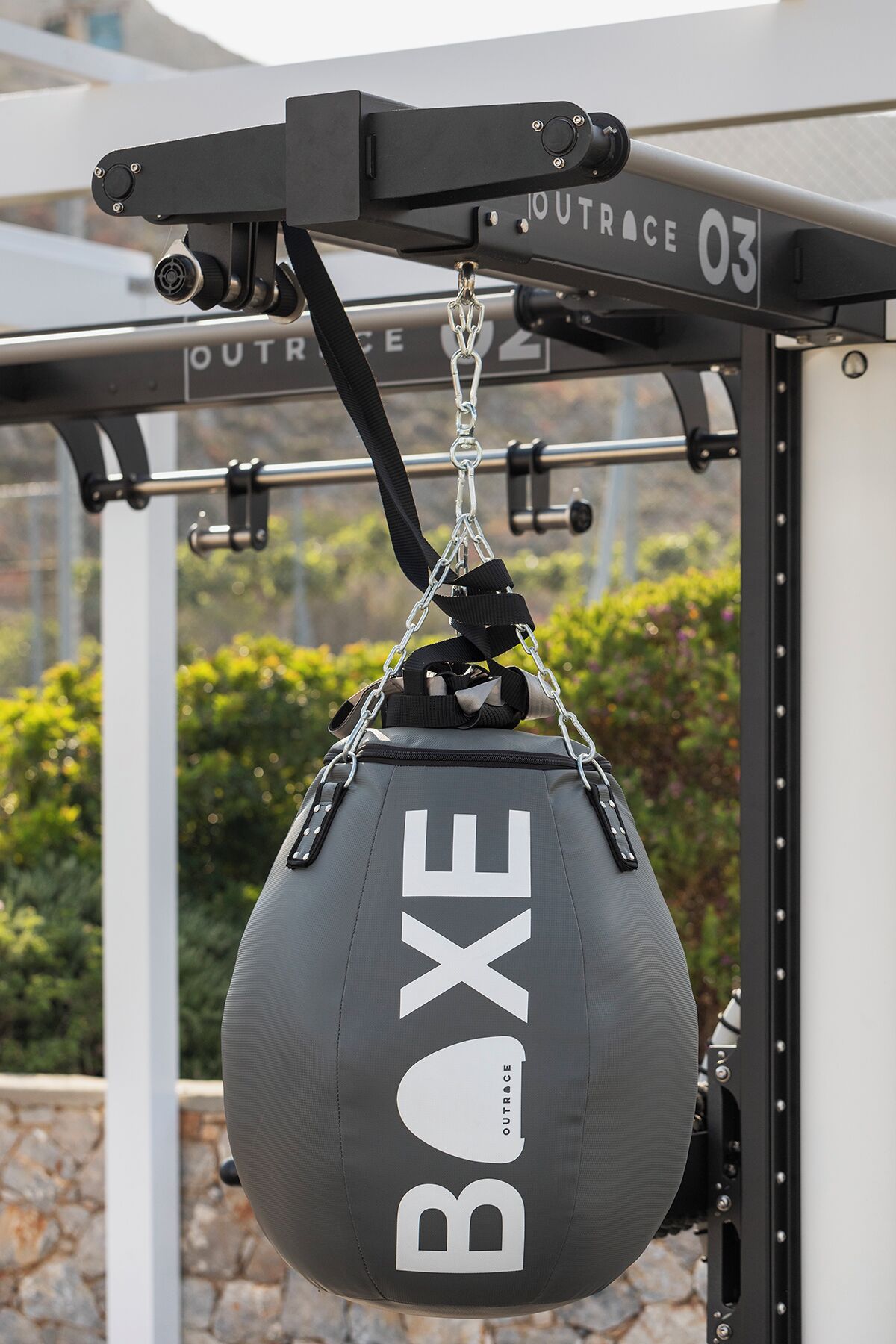 En sort boksepude med teksten "BOXE" hængende fra en metalkonstruktion, hvor der står "OUTRACE 03".