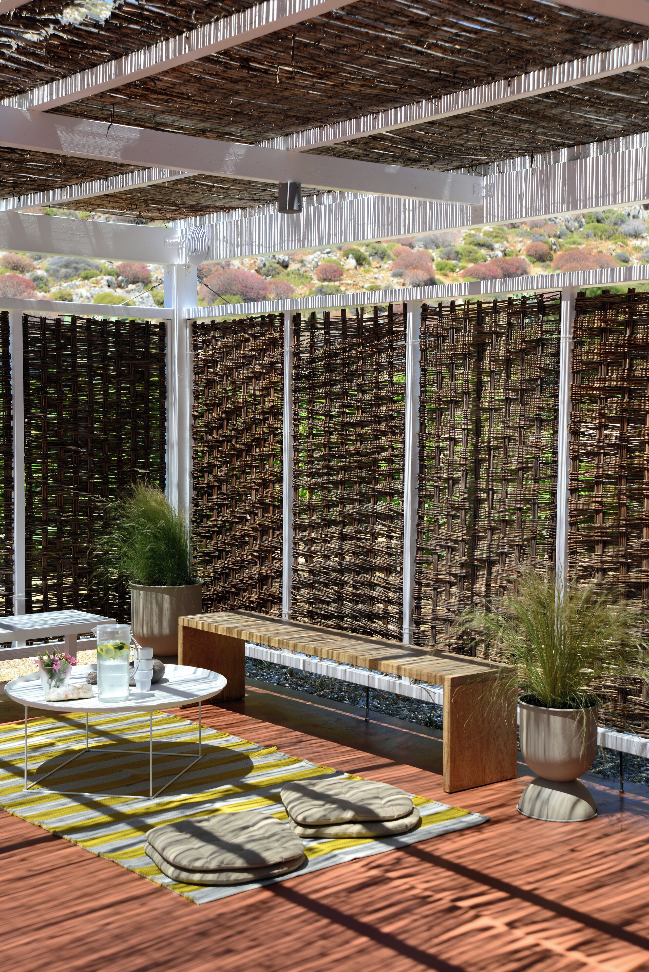 A modern outdoor seating area with a wooden deck, round tables, and potted plants.