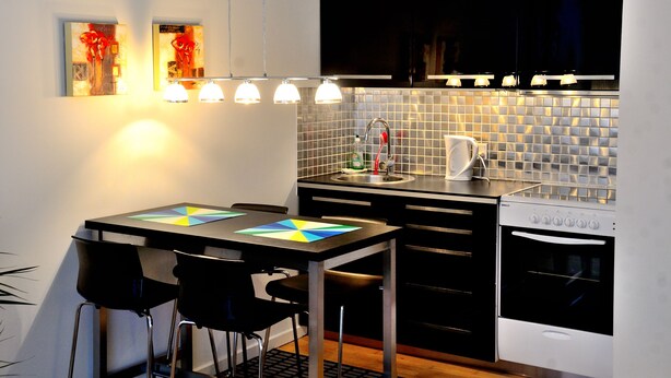 A modern kitchen with a dining table, chairs, a sink, and a stove. - Studio Rådmandsgade (Copenhagen)