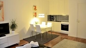A compact living space with a kitchenette, dining area, and a TV on a white cabinet. - Studio Rådmandsgade (Copenhagen)
