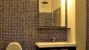 A bathroom with a toilet, sink, and mirror. - Studio Rådmandsgade (Copenhagen)