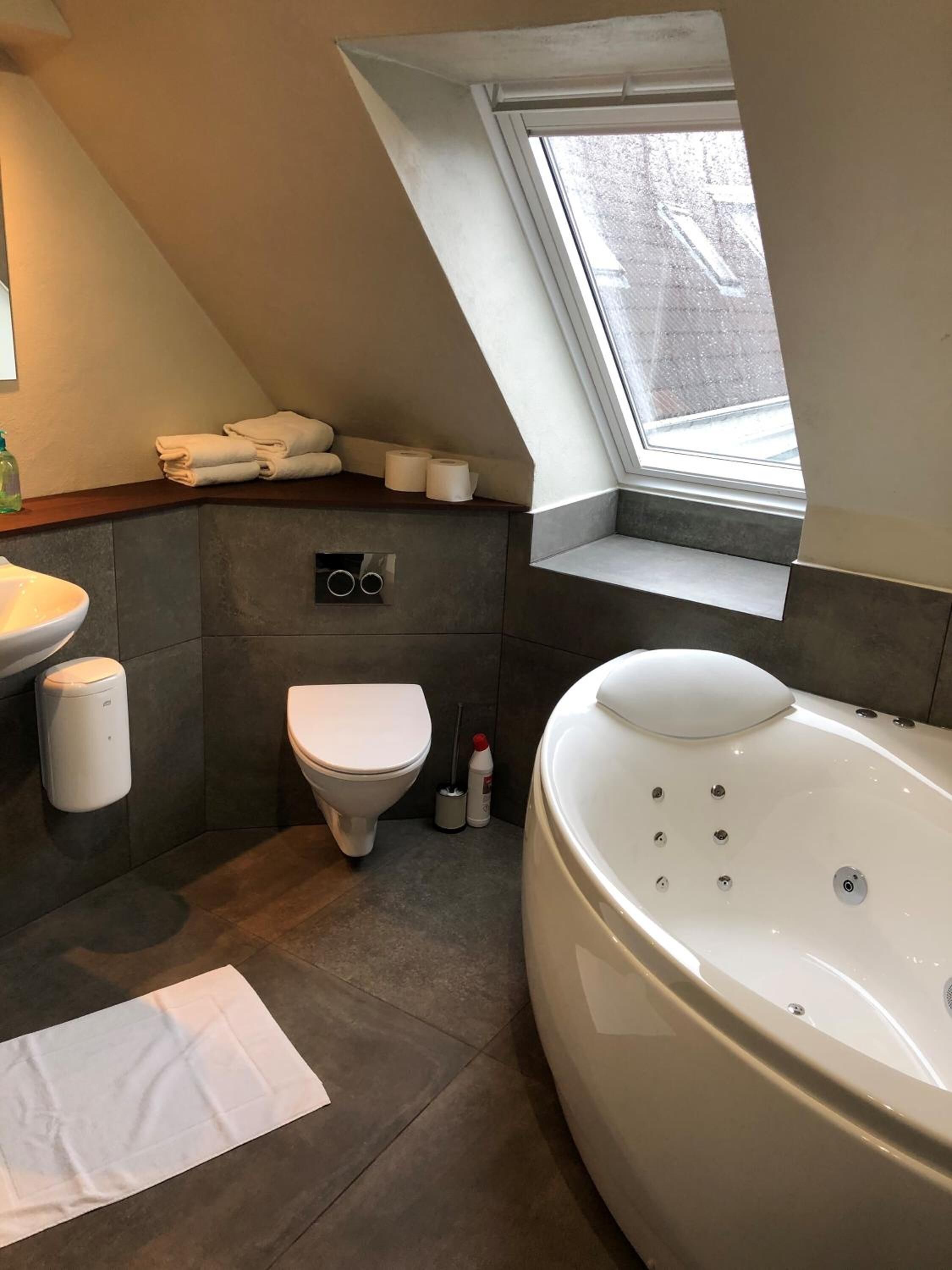 A modern bathroom with a freestanding bathtub, a toilet, a sink, and a window with a view of the outside.
