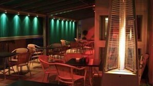 A dimly lit room with a central table and chairs, a green curtain backdrop, and a decorative light fixture. - Højslev Kro (Hojslev)