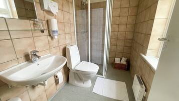 Un baño con lavamanos, inodoro y zona de ducha.