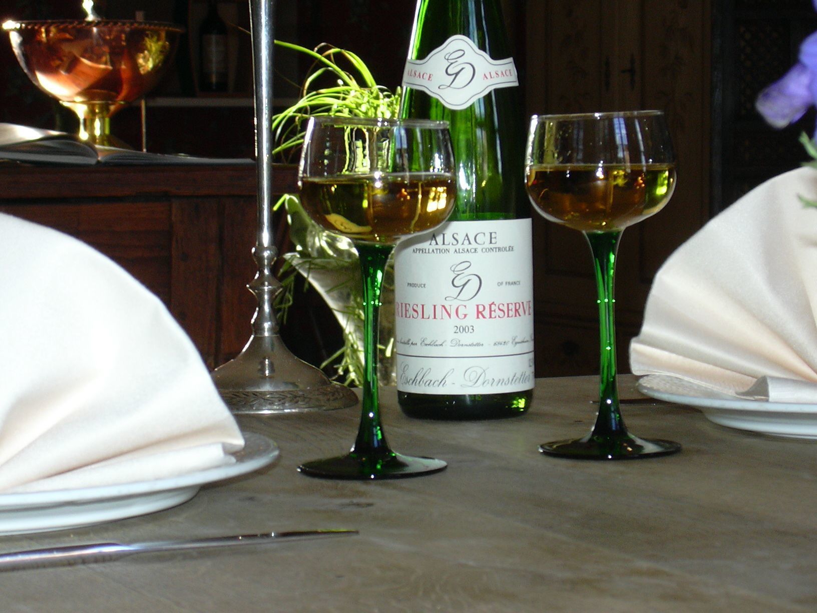A table set with wine glasses, a bottle of wine, and a bowl.