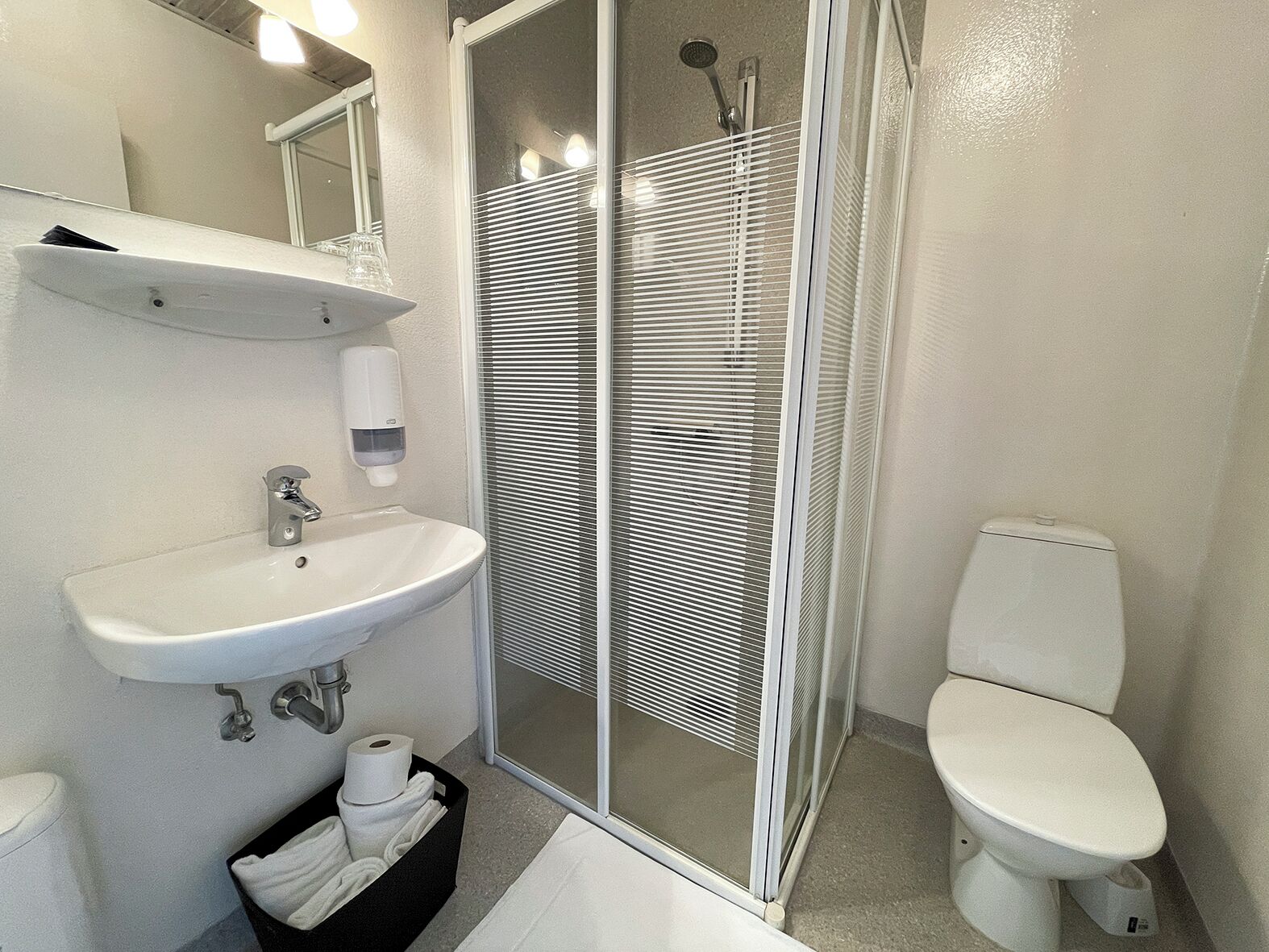 Ein modernes Badezimmer mit Waschbecken, Toilette und Duschkabine aus Glas.