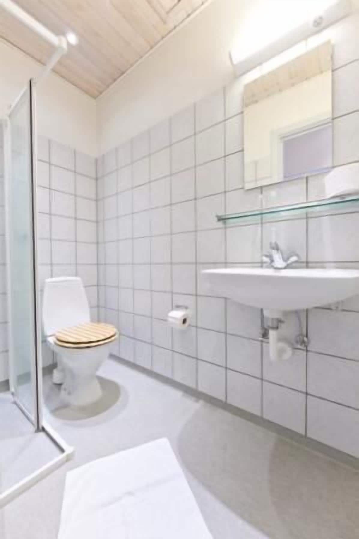 Un baño moderno con inodoro, lavamanos y espejo.