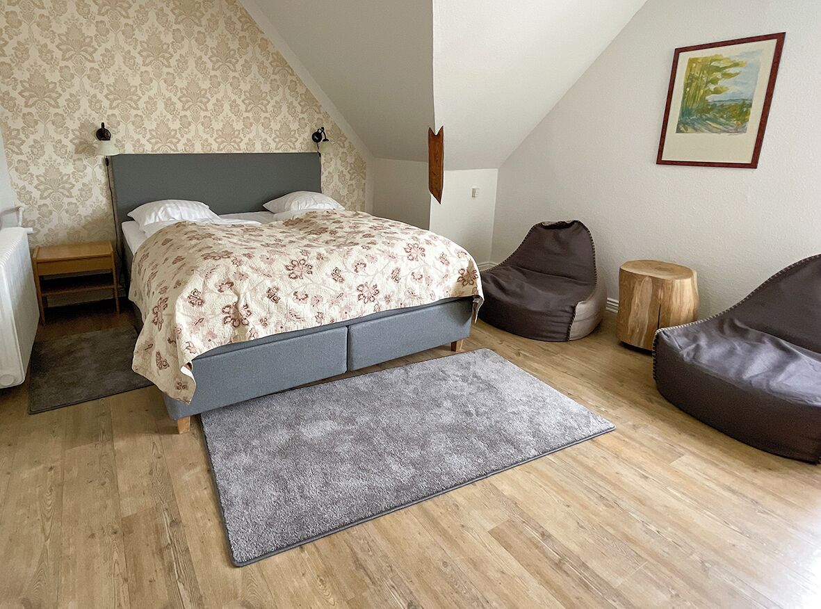 A bedroom with a bed, a chair, a small table, and a rug.