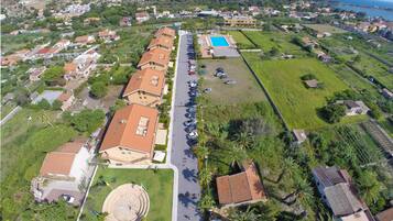 An aerial view of a residential area with houses, a swimming pool, and a road.